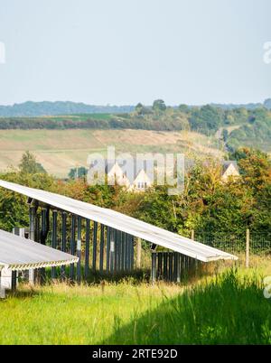 Side,detailed view of solar panels,working units,glowing with and reflecting late afternoon sunlight,showing distant countryside houses on the horizon Stock Photo