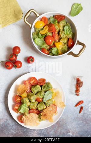 Strangolapreti (spinach-ricotta gnocchi, Italy) with tomatoes and parmesan wafers Stock Photo