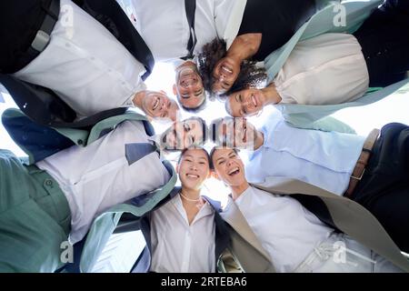 Multiracial diverse group office men women colleagues hugging in circle looking down smiling camera. Stock Photo