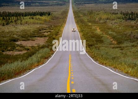 Truck driving down a long, straight road in a rural area, Alaska Highway, Alaska, USA; Alaska, United States of America Stock Photo