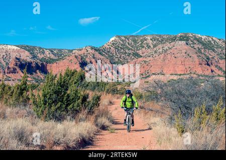 Man cycling through Caprock Canyons State Park and Trailway in Texas, USA; Quitaque, Texas, United States of America Stock Photo