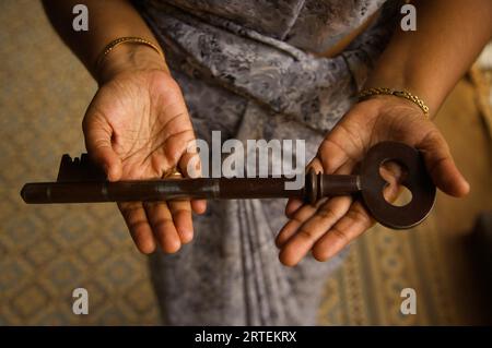 Woman holds out the large key to a mansion; Chettinad, Tamil Nadu, India Stock Photo