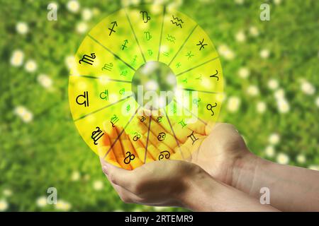 Astrology. Woman holding zodiac wheel on bright background, closeup Stock Photo