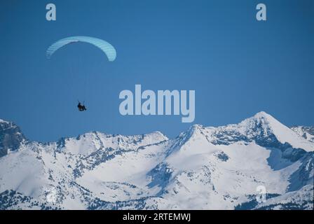 Paraglider glides past snow-covered Bald Mountain in Sun Valley, Idaho, USA; Sun Valley, Idaho, United States of America Stock Photo