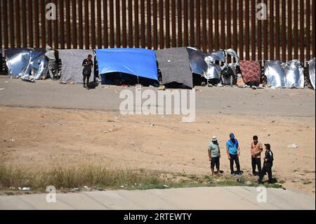 Tijuana, Baja California, Mexico. 12th Sep, 2023. Around a hundred people are stuck between the two US-Mexico border fences dividing Tijuana and San Diego on Tuesday, September 12, 2023, as viewed from Tijuana, Mexico. The migrants are from countries in South America, Central Asia, Eastern Europe and Africa. All are seeking a chance to enter the US via asylum status, as some lost patience in the process of getting appointments through the CBP One application and crossed illegally out of desperation, some waiting months. Migrants claim that the appointment system is over saturated and is di Stock Photo