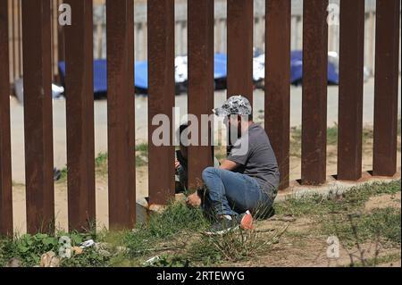 Tijuana, Baja California, Mexico. 12th Sep, 2023. Around a hundred people are stuck between the two US-Mexico border fences dividing Tijuana and San Diego on Tuesday, September 12, 2023, as viewed from Tijuana, Mexico. The migrants are from countries in South America, Central Asia, Eastern Europe and Africa. All are seeking a chance to enter the US via asylum status, as some lost patience in the process of getting appointments through the CBP One application and crossed illegally out of desperation, some waiting months. Migrants claim that the appointment system is over saturated and is di Stock Photo