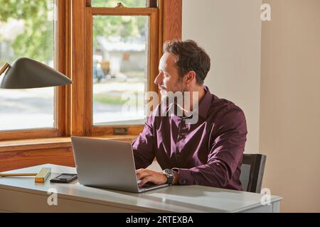 Man using laptop at desk at home Stock Photo