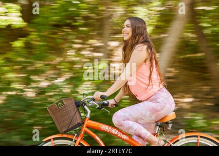 Smiling young woman riding bicycle in park Stock Photo