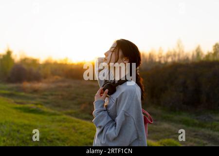Portrait of young woman with headphones on meadow at sunset Stock Photo