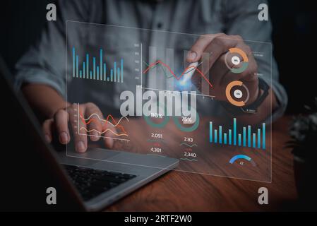 Man programmer using laptop analyzing marketing and development information and Data Management System virtual interface screen.Business Intelligence Stock Photo