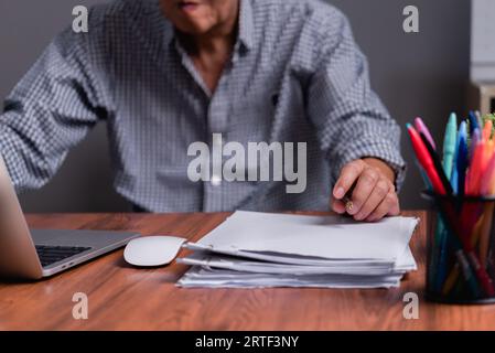 Asian senior businessman checking work papers and business reports Stock Photo