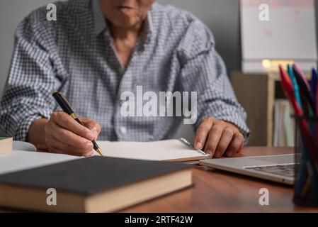 Asian senior businessman taking notes on business report Stock Photo