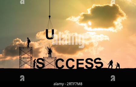 Silhouette of construction workers as a team working together to put letters as a word success on bright sky background Stock Photo