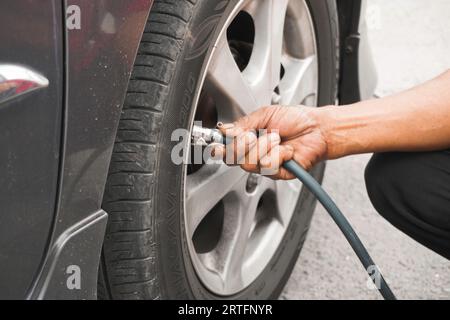 Klaten, Indonesia - August 17 2023: man driver hand inflating tires of vehicle, removing tire valve nitrogen cap for checking air pressure and filling Stock Photo