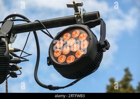 LED floodlight with RGB colors as outdoor stage lightning, installed on a black steel beam against the blue sky, used for festivals, music concerts, p Stock Photo