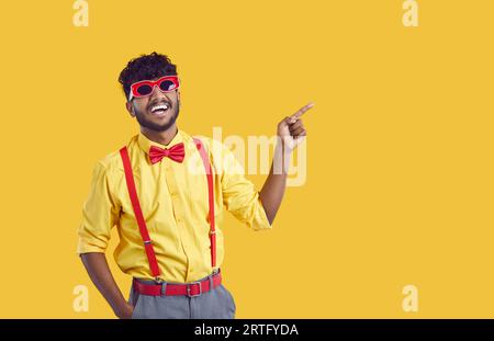 Young cheerful Indian man student in funny sunglasses for party pointing with finger at copy space Stock Photo