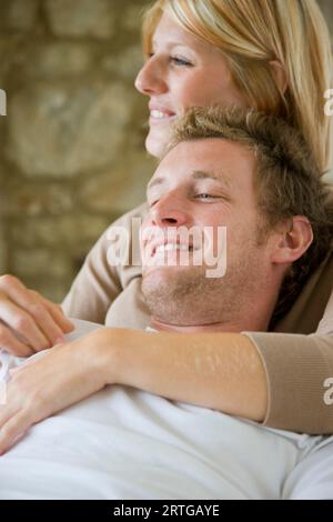 Smiling blonde woman hugging boyfriend from behind Stock Photo - Alamy