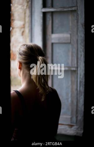 Back view of a woman looking out of a window Stock Photo