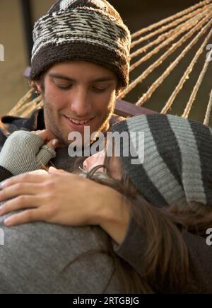 Young couple lying on hammock embracing and looking at each other Stock Photo