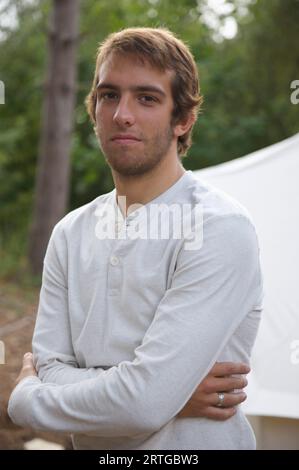 Young man standing by a tent with his arms crossed Stock Photo