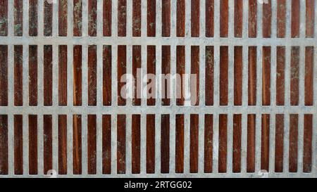 lattice metal mesh of long strips on a dark dirty background as a grunge graphic resource, iron mesh with thick crossbars with a dark backdrop Stock Photo