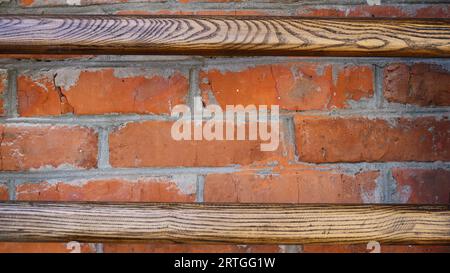 composite background of old red brick with cement joints and wooden varnished thin planks as a texture of rough dark materials, mixed texture Stock Photo