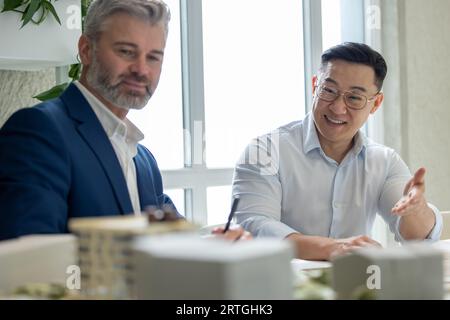 Men architects working on construction plans, engineers discussing on project in office. Stock Photo
