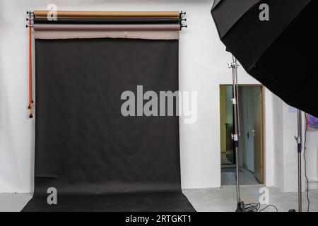 interior of bright space of photo studio with large black background and lighting equipment Stock Photo