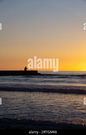 paisaje de pescador en el mar con caña de pescar al atardecer Stock Photo