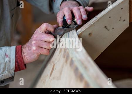 Hands of an artisan boat builder of wooden boats using traditional small plane Stock Photo