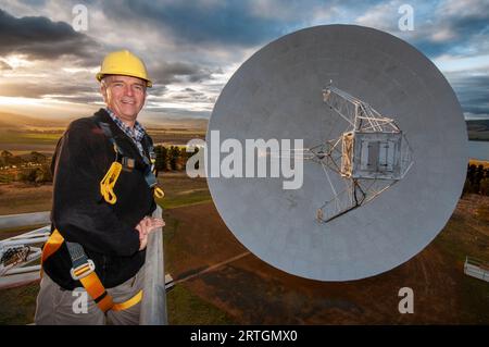 Brett Reid, Observatory Manager on a cherry picker above the main dish of the ex-NASA, UTAS radio telescope at Mt Pleasant in Tasmania Stock Photo