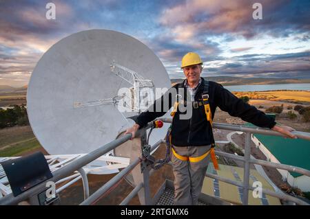 Brett Reid, Observatory Manager on a cherry picker above the main dish of the ex-NASA, UTAS radio telescope at Mt Pleasant in Tasmania Stock Photo