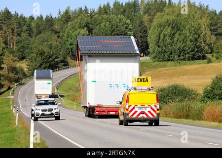 Two exceptional load transports of a prefab cabin in highway traffic, escort vehicle assisting, car gives way. Salo, Finland. September 7, 2023. Stock Photo