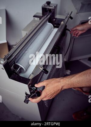 Crop unrecognizable male worker checking machine while using electric tool during work process Stock Photo