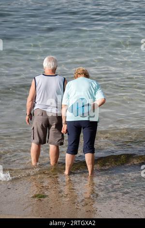 Elderly couple paddling in sea Stock Photo