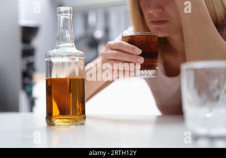 Drunk depressed alcoholic woman drinking whiskey alone at home Stock Photo