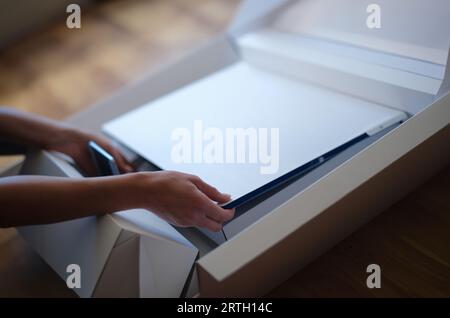 Tbilisi, Georgia - May 25, 2022: Woman removes white protective film from New iMac monitor Stock Photo