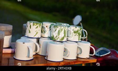 Several Enamel Coffee Mugs are arranged and stacked upside down on the table. Stock Photo