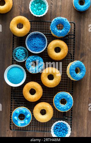 Many plain and blue decorated donuts against a dark background. Stock Photo