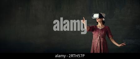 Elegant medieval person, maid in historical dress wearing vr glasses against dark vintage background Stock Photo