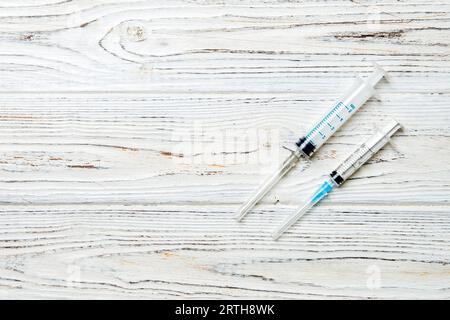 Top view of syringes of different sizes on wooden background. Medical equipment for injection concept with copy space. Stock Photo