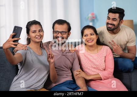 Cheerful indian middle aged parents with siblings taking selfie on mobile phone at home - concept of family togetherness, technology reunion and Happy Stock Photo