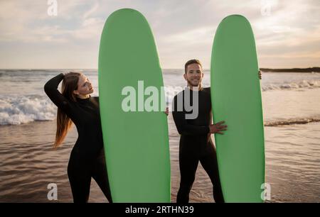 Summer Activities. Happy Young Couple Posing With Surfboards On The Beach Stock Photo