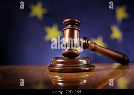 Mahogany wooden gavel on glossy wooden table. Flag of European Union, EU, in the background