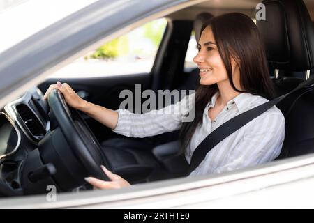 Happy attractive young woman driving white car Stock Photo