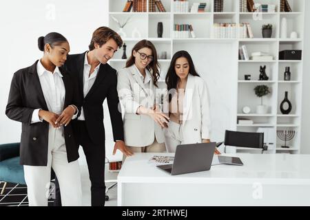 Teamwork and unity. Professional international business team of four specialists working together on laptop computer Stock Photo