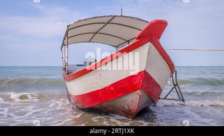 Longtail boat with red and white stripes waiting for passengers on beautiful monkey beach in Penang national park, Malaysia Stock Photo