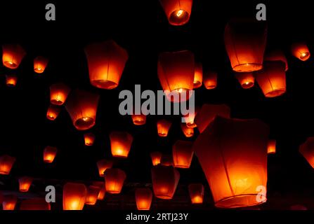 Glowing orange paper lanterns illuminate the night sky during the Pingsi sky lantern festival in Taiwan Stock Photo