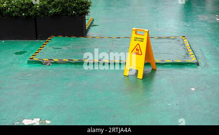 Sign showing warning of caution wet floor, Yellow sign that alerts for wet floor, Warning symbol of slippy floor for pedestrian. Stock Photo