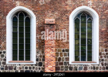 Two arched windows with metal bars and white edging on an old red brick wall. From the Windows of the world series. Stock Photo